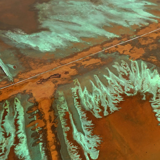 Close-up of copper patina with vivid green tones and natural patterning, sealed under a car lacquer.