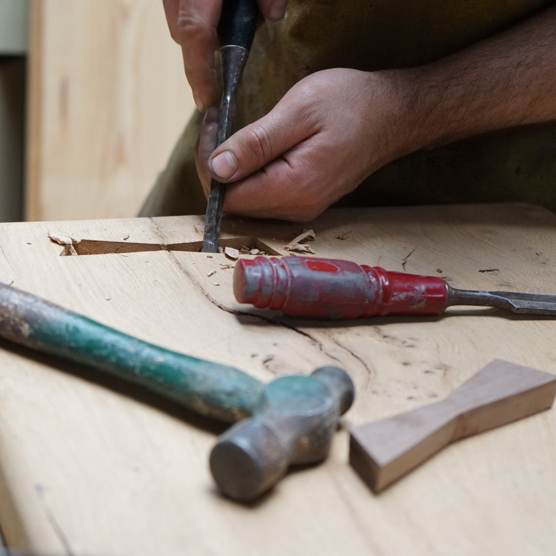Close-up of a person working with tools on a pine dining table top creating a bow tie.