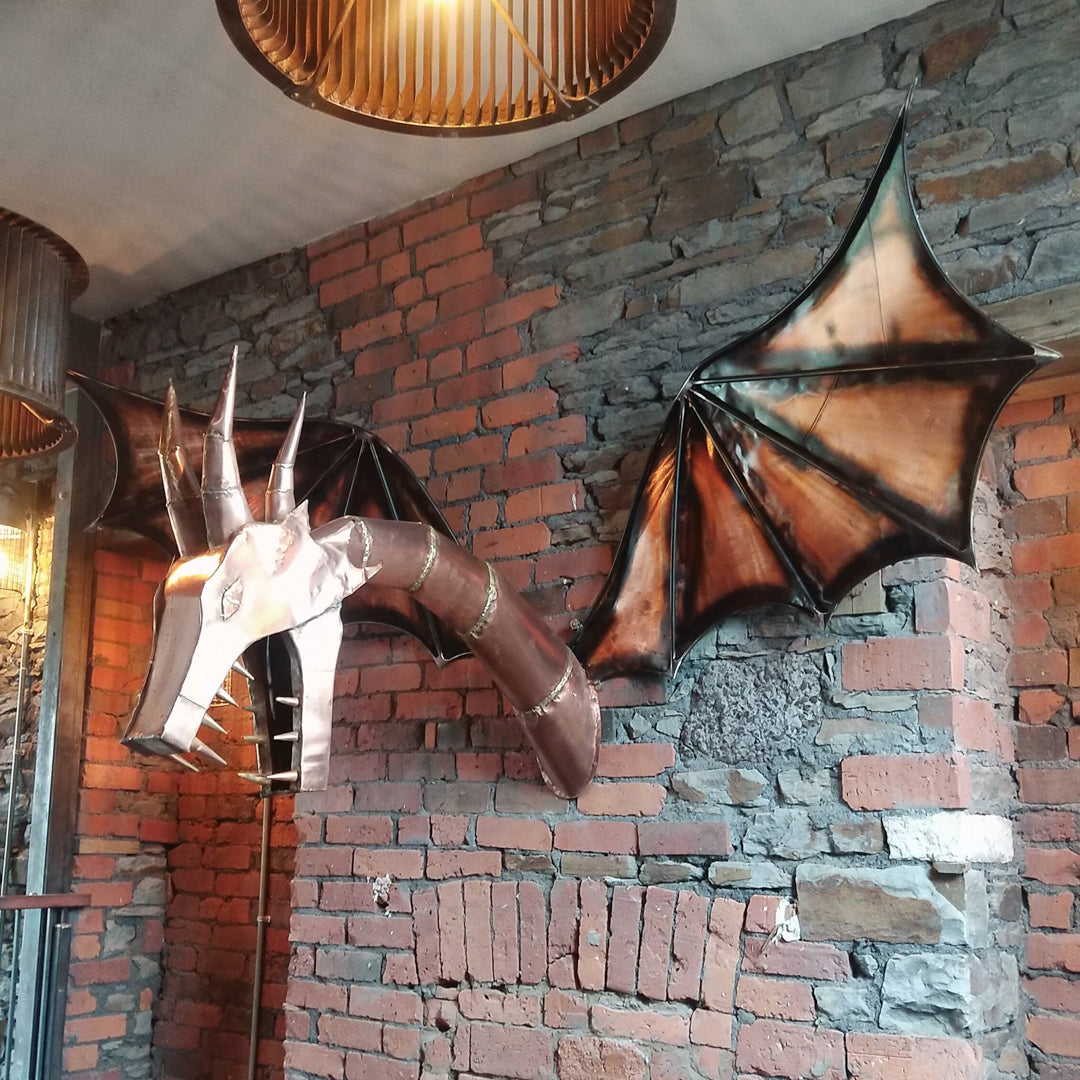 Copper and steel dragon sculpture mounted on a rustic brick wall.