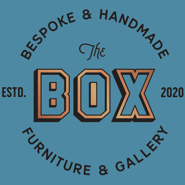 Logo of "The BOX Furniture and Gallery" on a blue background.