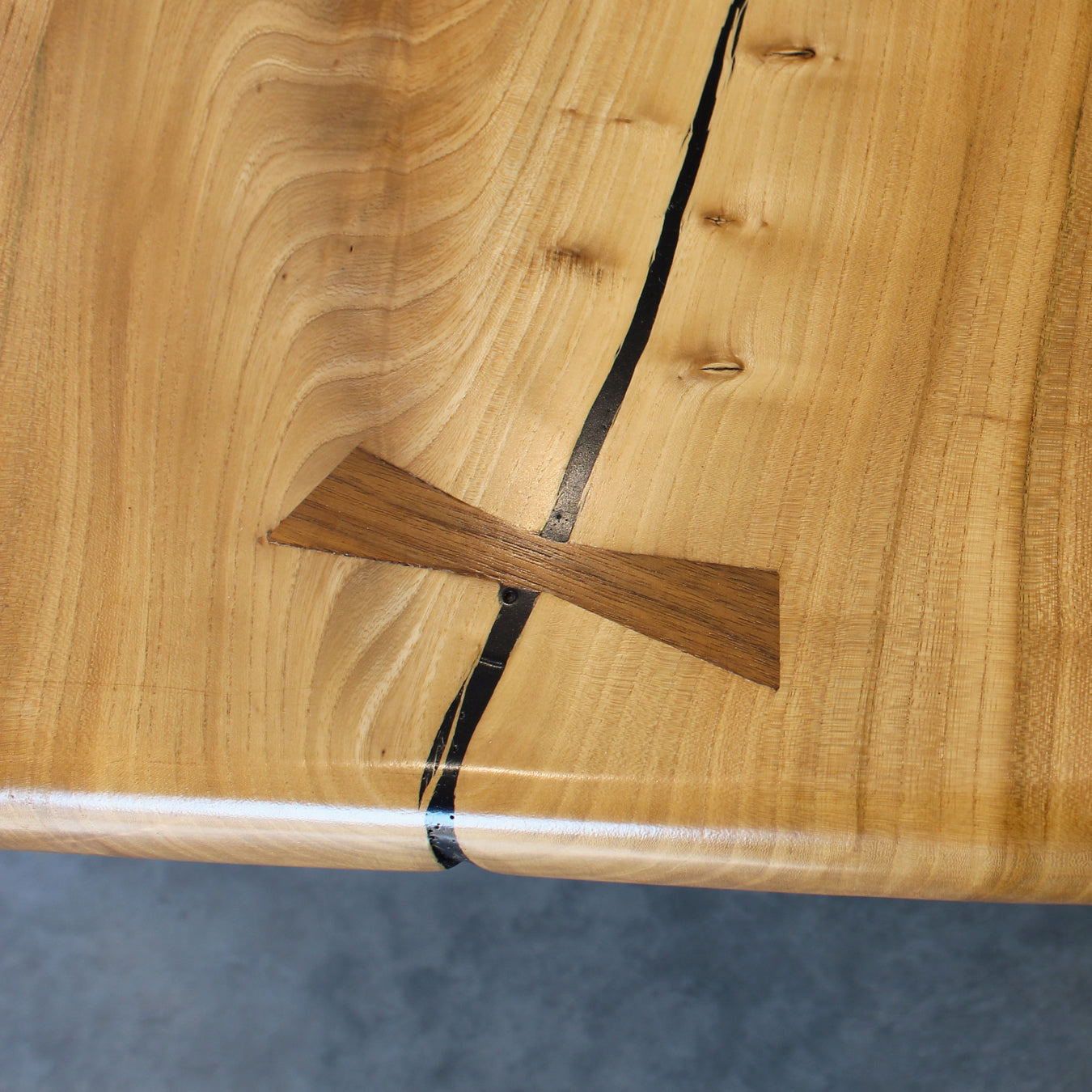 Focused view of a bowtie inlay securing a natural split in the elm, adding artisanal charm.