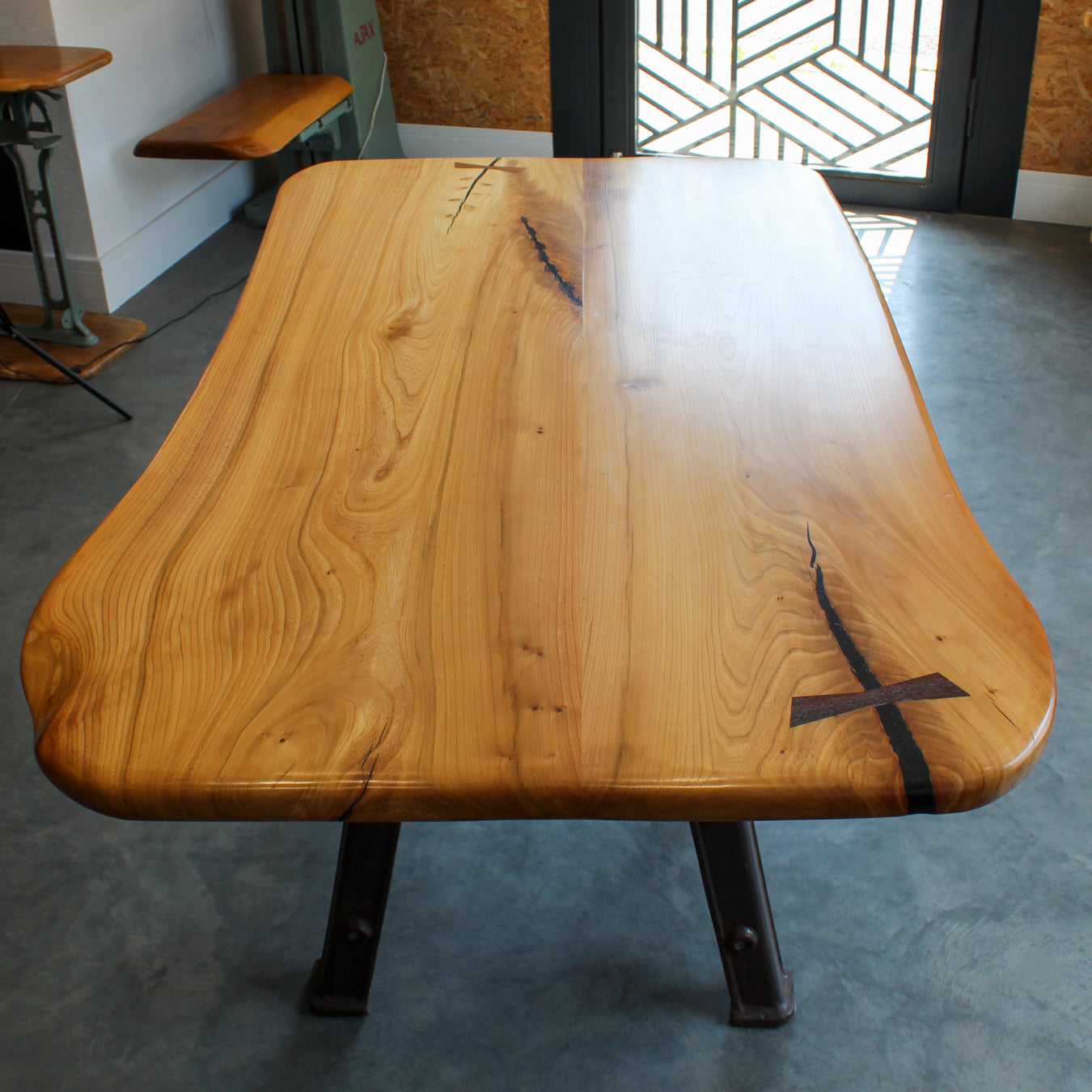 Angled view of the Bamford Table showing the smooth elm surface and sturdy cast iron base.