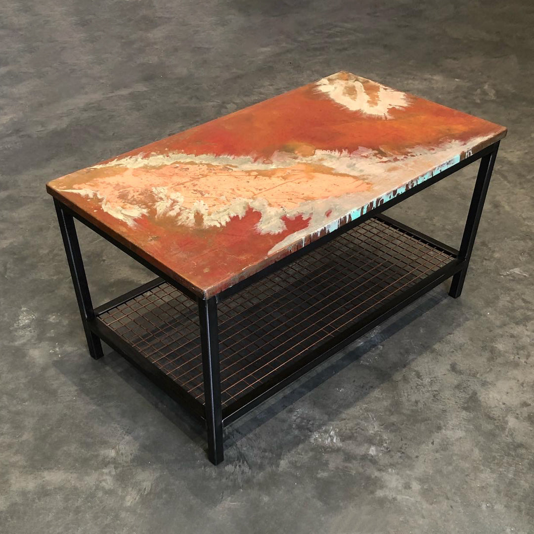 Coffee table with a unique copper top featuring bright red, orange and white colourings in an obscure pattern.